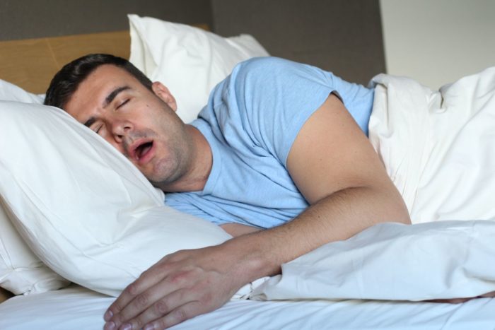 Man sleeping and snoring in bed sleep apnea dentist in Roslyn Heights New York